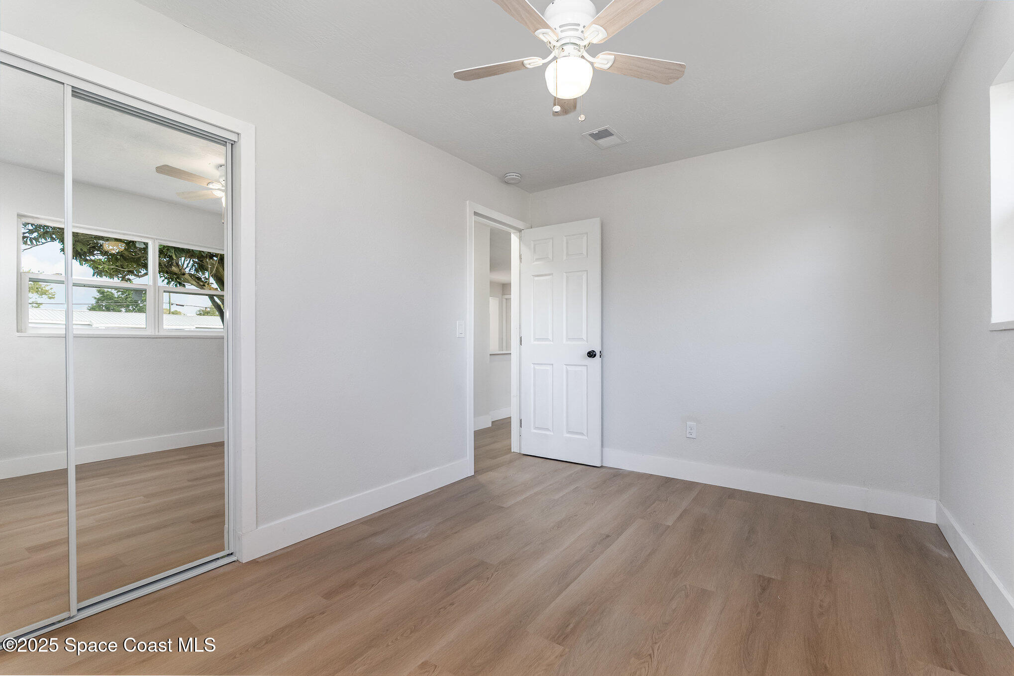 1029 Illinois Road Cocoa, FL 32927 - Photo 17 of 27 an empty room with wooden floor closet and windows
