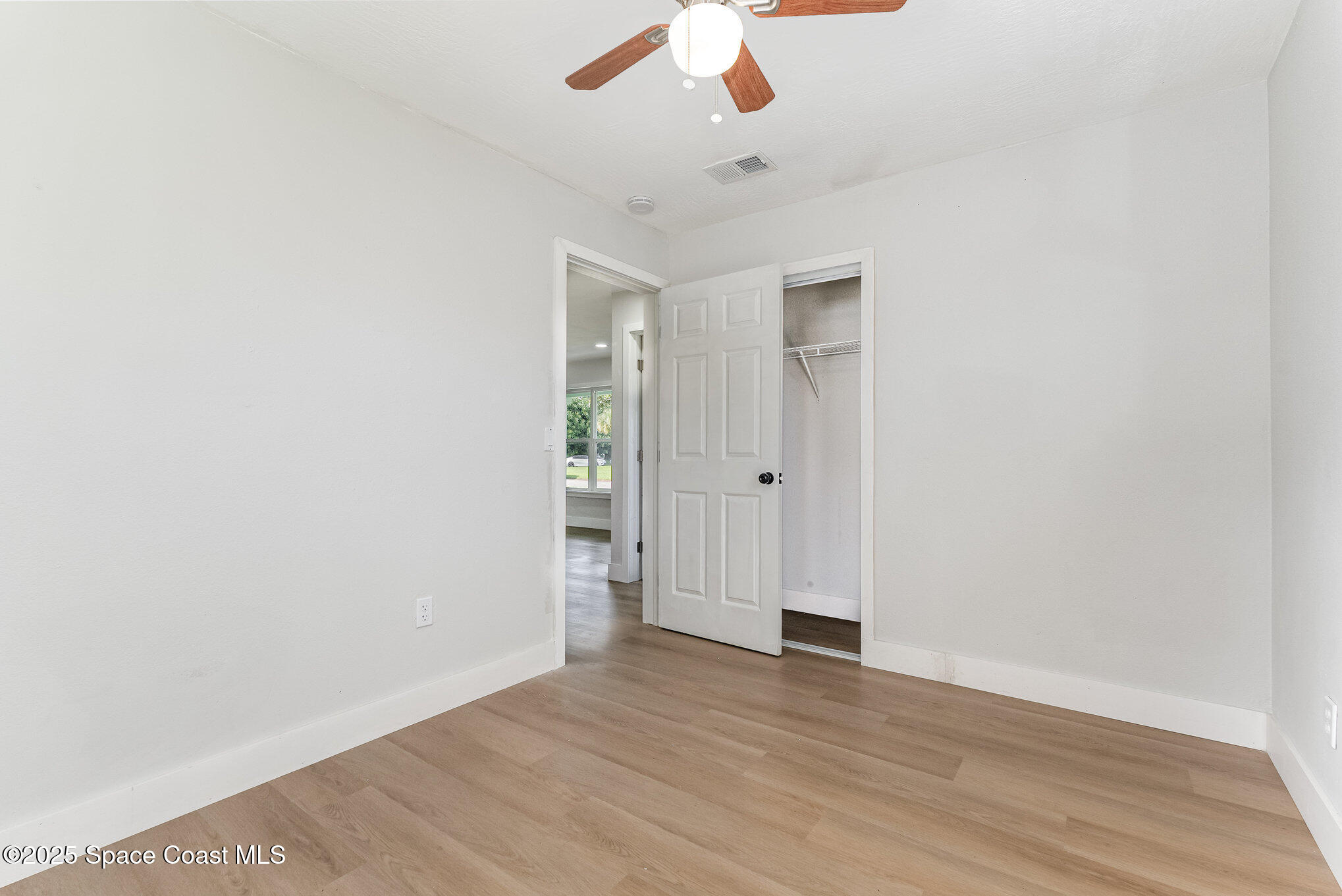 1029 Illinois Road Cocoa, FL 32927 - Photo 18 of 27 an empty room with wooden floor chandelier fan and windows