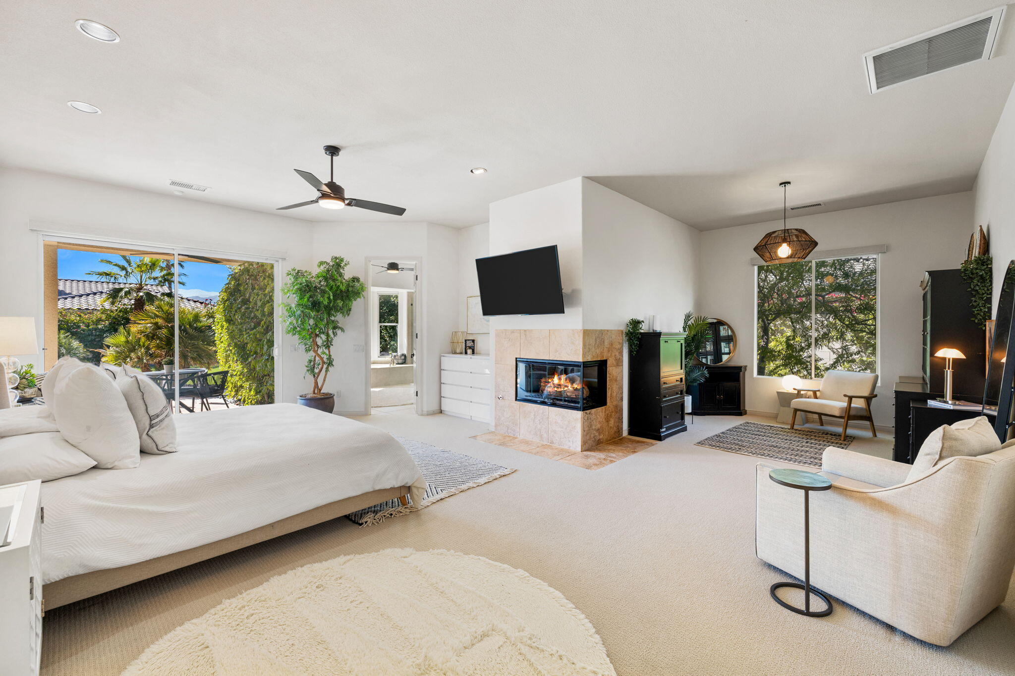 19 Trafagar Square Rancho Mirage, CA 92270 - Photo 30 of 54 a bedroom with a large bed flat screen tv and a fireplace