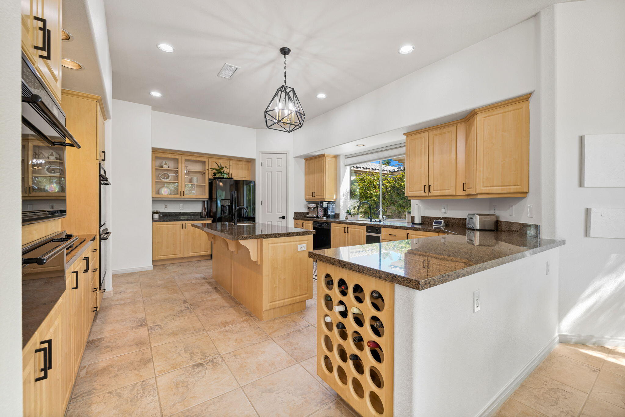 19 Trafagar Square Rancho Mirage, CA 92270 - Photo 3 of 54 a large kitchen with kitchen island a large counter space a sink a window and stainless steel appliances
