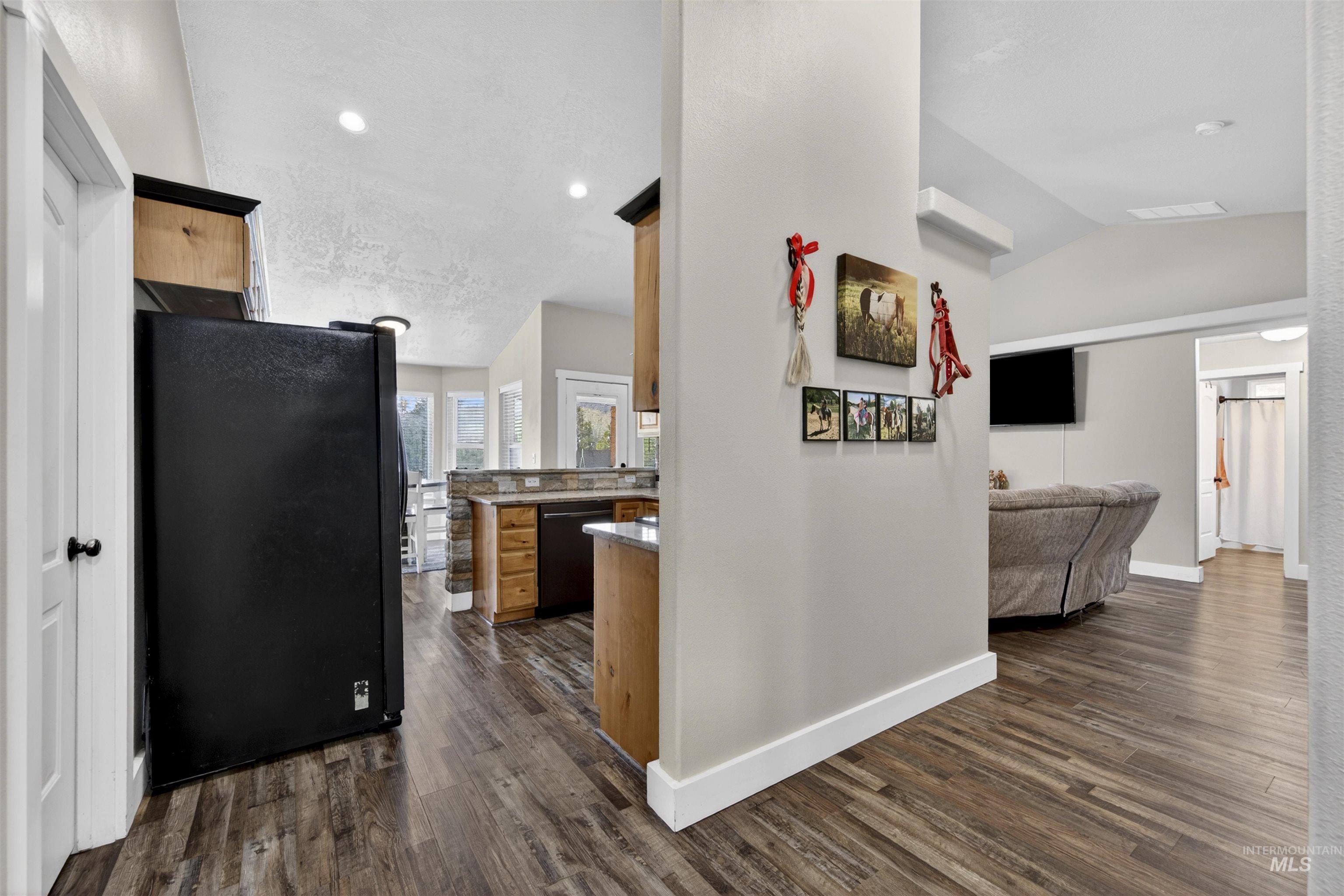 4 Round Up Circle Boise, ID 83716 - Photo 20 of 47 Open-concept living space featuring wood-finish flooring, a vaulted ceiling, recessed lighting, and a kitchen area with light wood cabinetry and a stone-clad breakfast bar