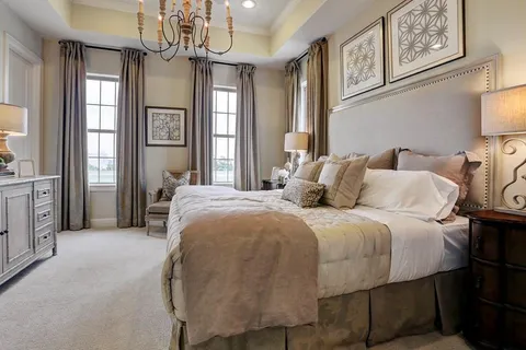 a spacious bedroom with a bed a chandelier and a window