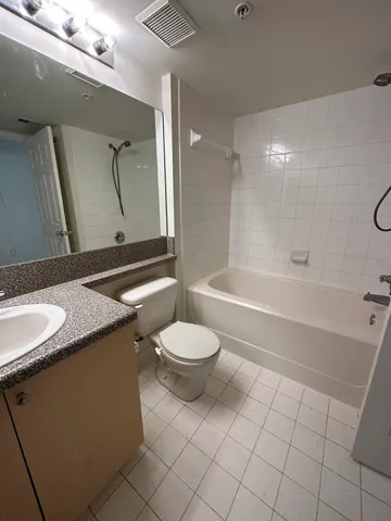 a bathroom with a granite countertop sink toilet a mirror and shower