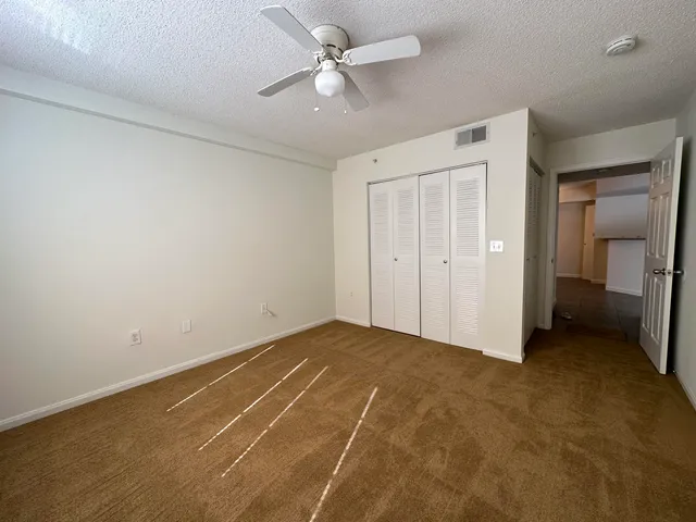 an empty room with closet and a ceiling fan