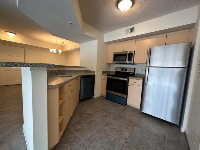 a kitchen with stainless steel appliances granite countertop a refrigerator a sink and a stove