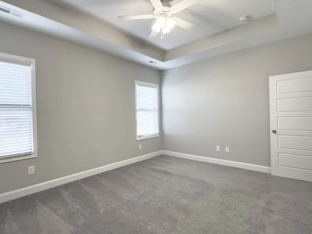 an empty room with windows and chandelier fan