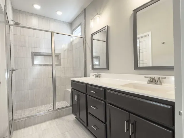 a bathroom with a double vanity sink mirror and shower