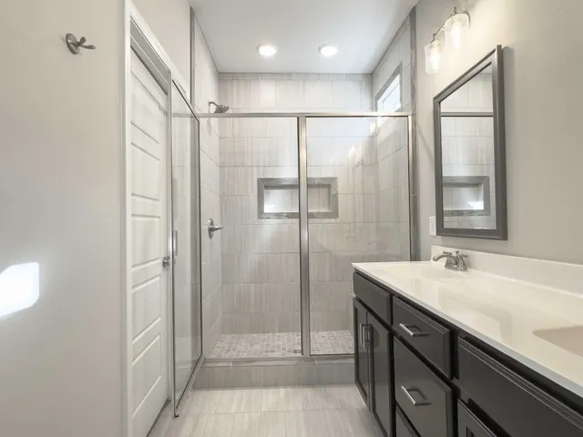 a bathroom with a shower sink vanity and mirror