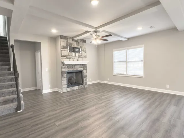 an empty room with wooden floor fireplace and windows