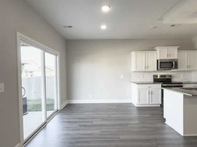 a view of a kitchen with wooden floor and electronic appliances