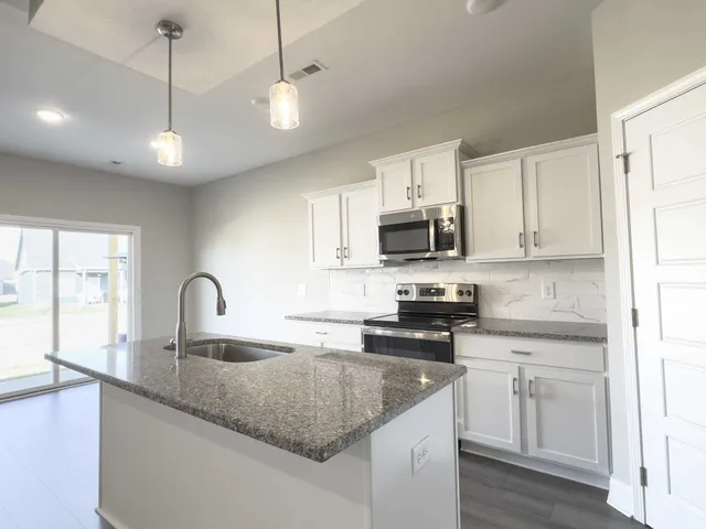 a kitchen with stainless steel appliances granite countertop a sink a stove and a granite counter tops with wooden floors