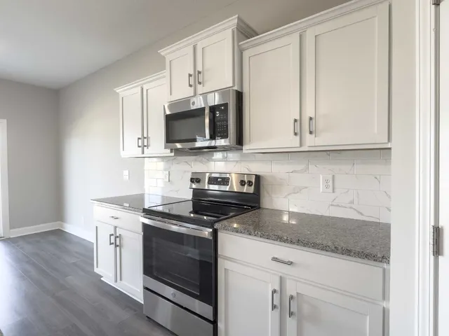 a kitchen with granite countertop white cabinets and stainless steel appliances