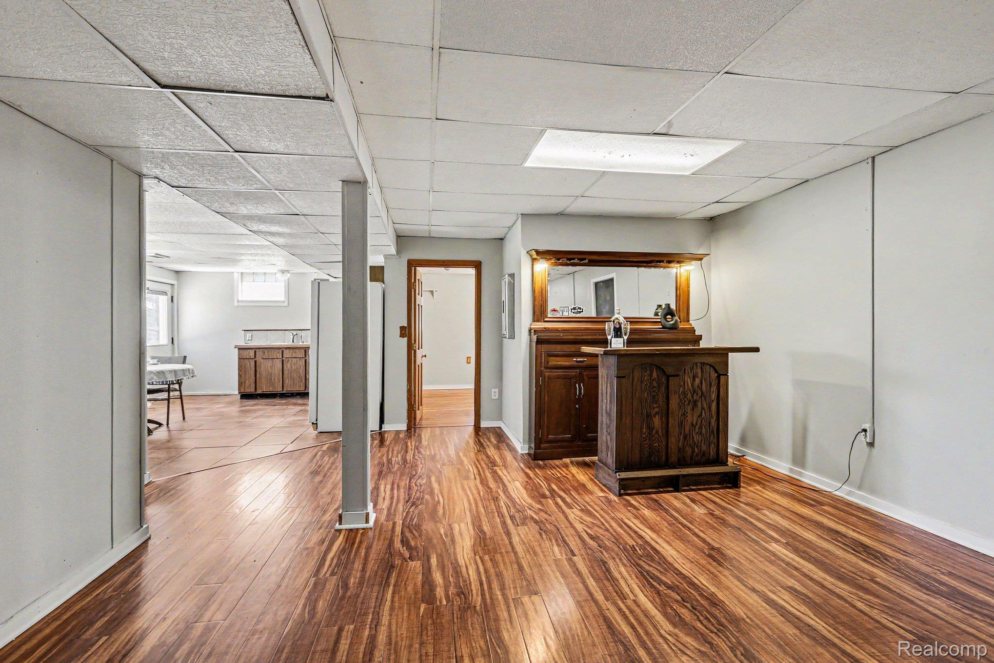 1405 Swarthout Road Pinckney, MI 48169 - Photo 16 of 31 Bar area featuring freestanding refrigerator, dark wood-style flooring, a paneled ceiling, and dark wood finish cabinetry