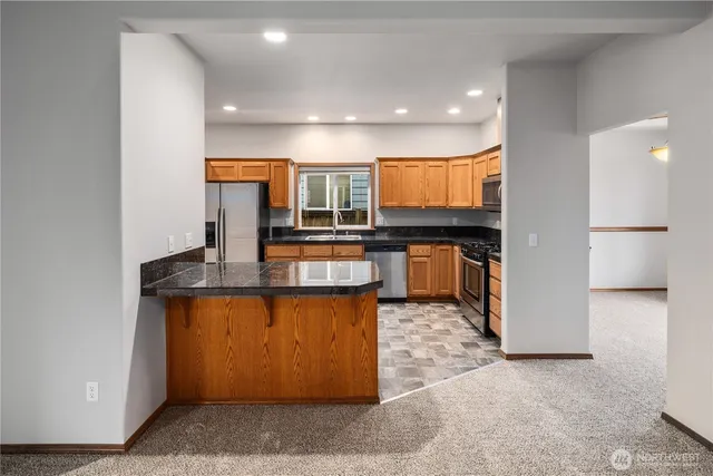 a kitchen with stainless steel appliances granite countertop a stove a sink and a refrigerator