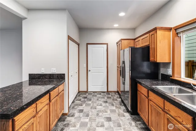 a kitchen with stainless steel appliances granite countertop a refrigerator a sink and wooden cabinets