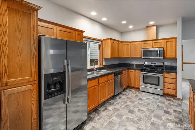 a kitchen with stainless steel appliances granite countertop a refrigerator and a stove top oven