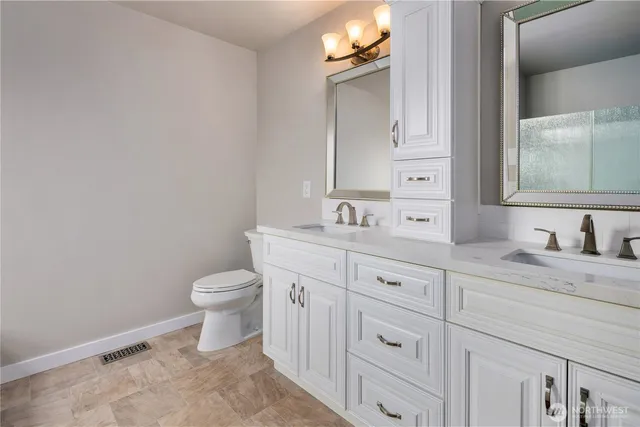 a bathroom with a granite countertop toilet sink and mirror