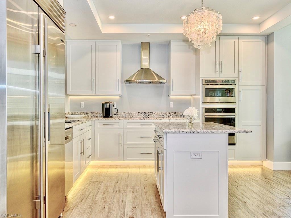60 Seagate Drive, Unit 406 Naples, FL 34103 - Photo 6 of 26 a kitchen with stainless steel appliances granite countertop a stove oven and a refrigerator with white cabinets