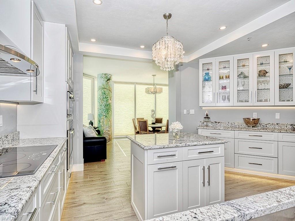 60 Seagate Drive, Unit 406 Naples, FL 34103 - Photo 8 of 26 a large kitchen with kitchen island granite countertop a sink a stove and cabinets