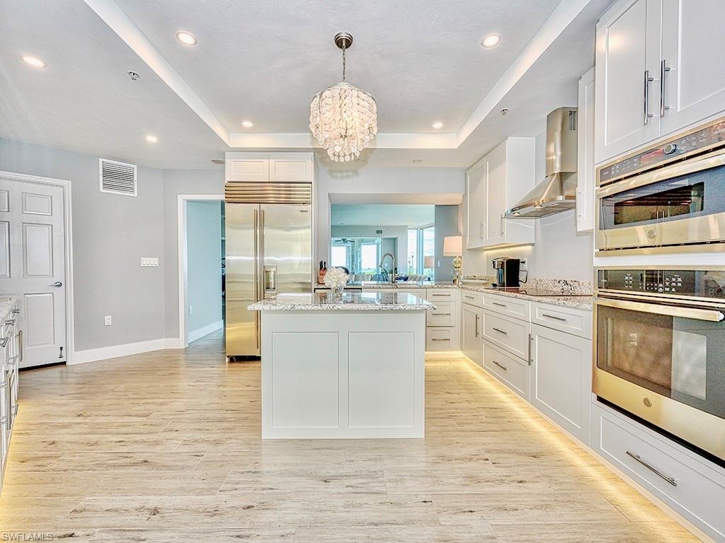 60 Seagate Drive, Unit 406 Naples, FL 34103 - Photo 9 of 26 a large kitchen with kitchen island a stove a sink a refrigerator dining table and chairs
