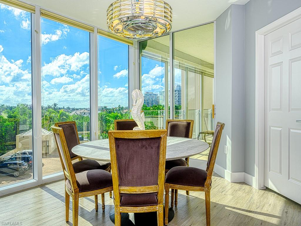 60 Seagate Drive, Unit 406 Naples, FL 34103 - Photo 10 of 26 a view of a dining room with furniture a chandelier and wooden floor