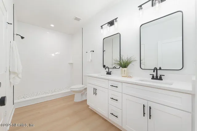 a bathroom with a double vanity sink mirror and toilet