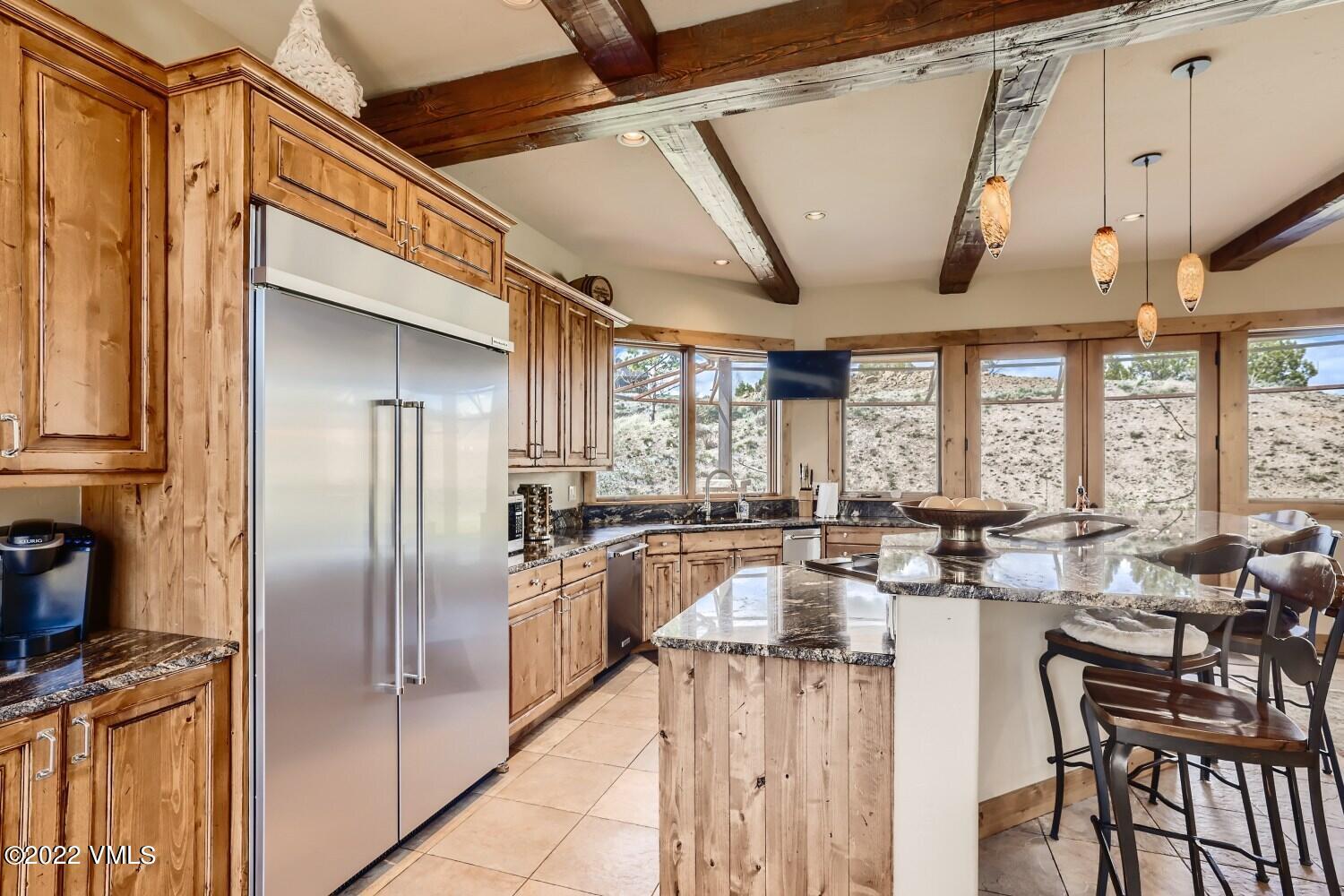 290 Amherst Road Gypsum, CO 81637 - Photo 6 of 32 a kitchen with stainless steel appliances granite countertop a refrigerator a stove and a dining table with wooden floors