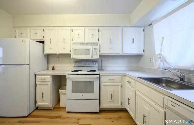 a kitchen with white cabinets and white appliances