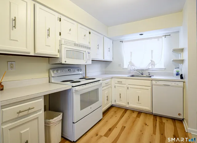 a kitchen with granite countertop white cabinets sink and stainless steel appliances