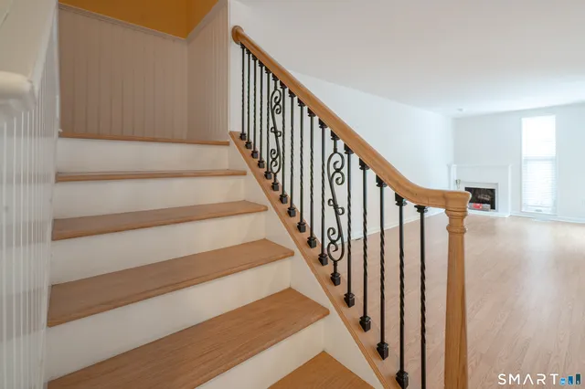 a view of staircase with lots of frames on wall and wooden floor