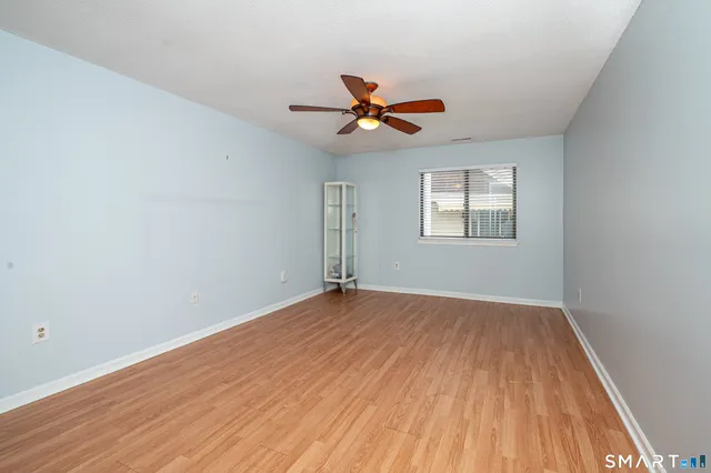 an empty room with wooden floor ceiling fan and windows