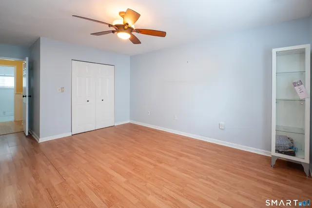 a view of empty room with wooden floor and fan