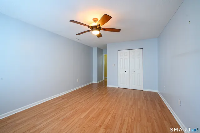 a view of an empty room with window and wooden floor