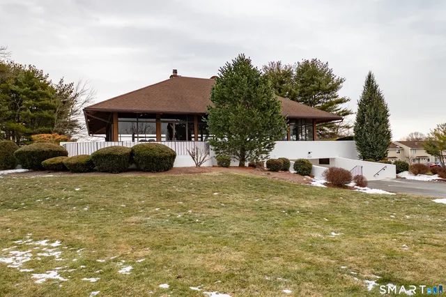 a front view of a house with a garden and trees