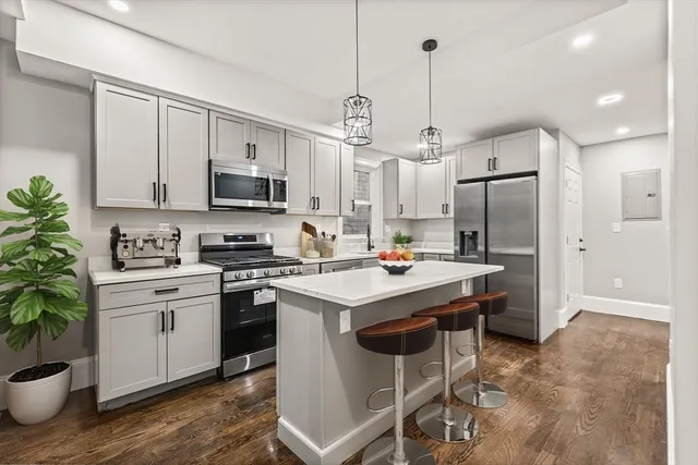 a kitchen that has a lot of white cabinets and stainless steel appliances