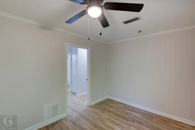 an empty room with wooden floor ceiling fan and window