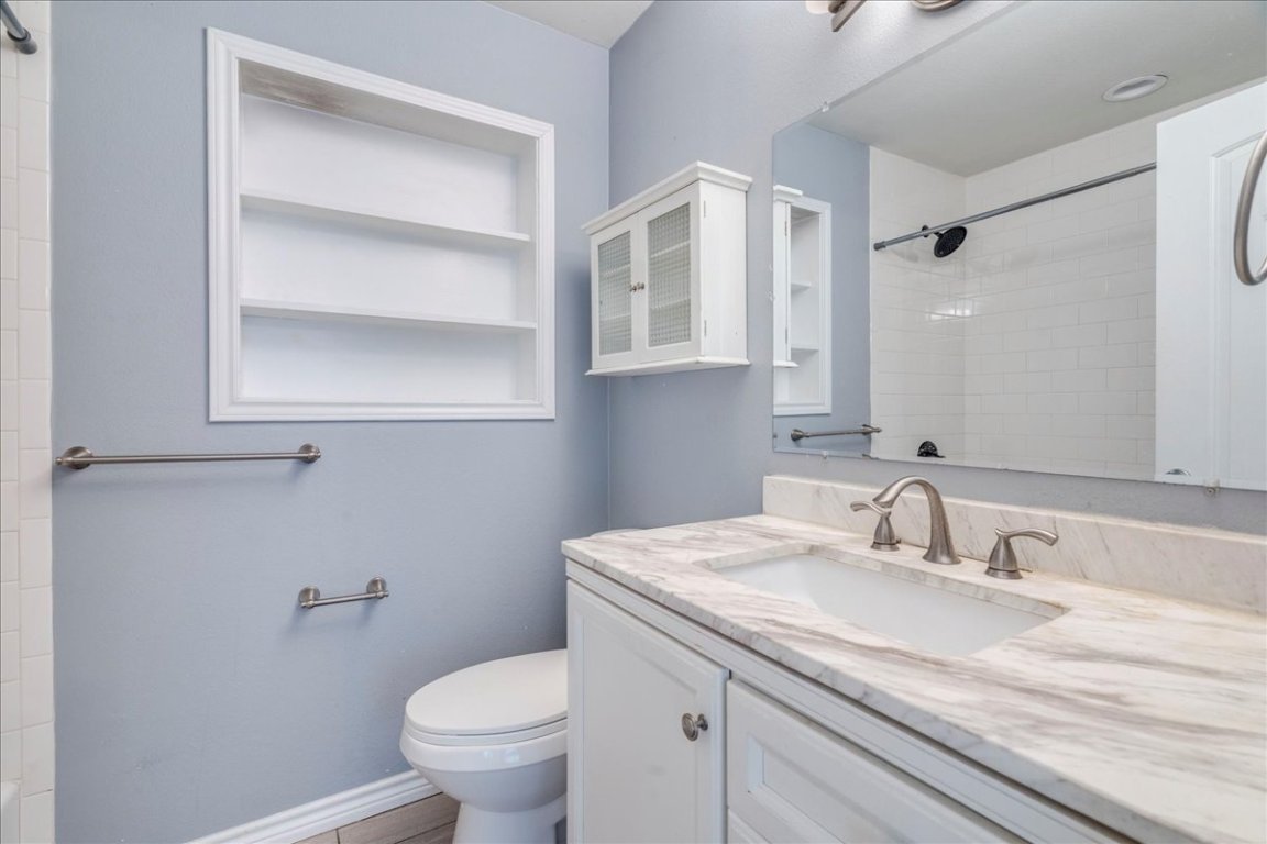 4712 Frontier Trail Austin, TX 78745 - Photo 18 of 32 a bathroom with a granite countertop sink a toilet and a mirror