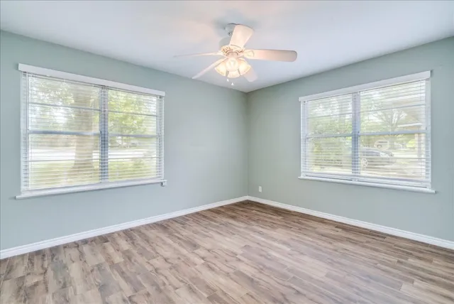 a view of an empty room with wooden floor and a window