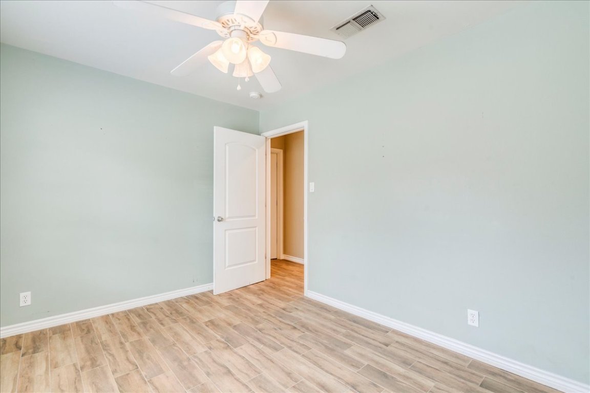 4712 Frontier Trail Austin, TX 78745 - Photo 22 of 32 an empty room with a chandelier fan and wooden floor