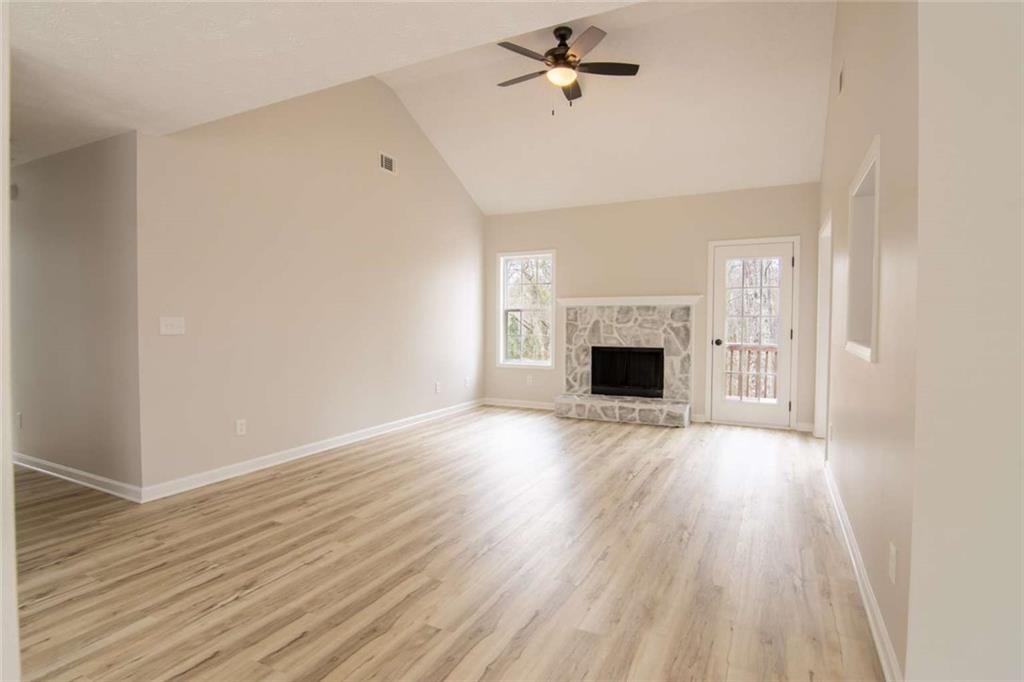 824 Eastmont Road Winder, GA 30680 - Photo 8 of 35 an empty room with wooden floor fireplace and windows
