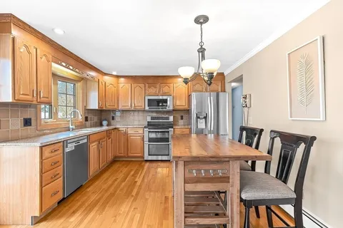 a kitchen with stainless steel appliances granite countertop a kitchen island hardwood floor sink stove dining table and chairs