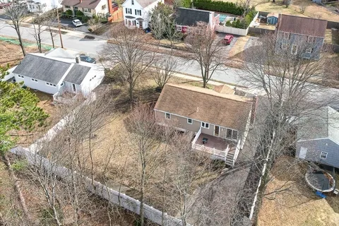an aerial view of a house with a yard and lawn chairs under an umbrella