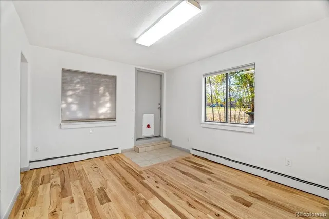a view of an empty room with wooden floor and a window