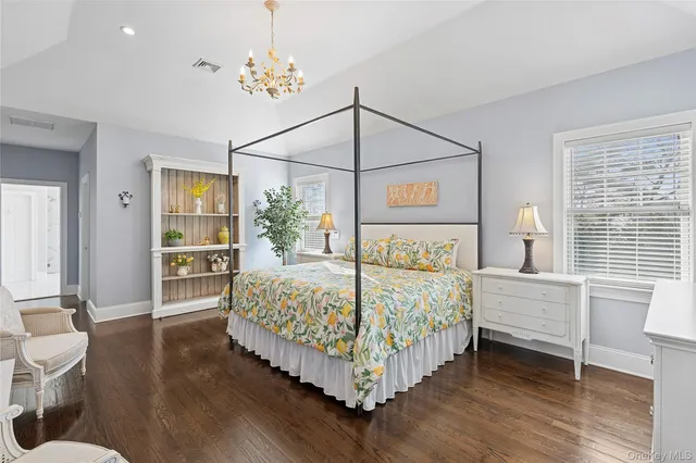 a bedroom with a large bed a chandelier and dresser