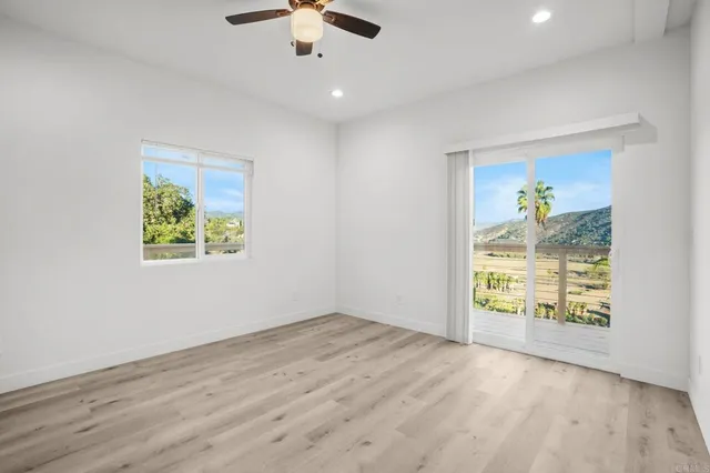 an empty room with windows and chandelier fan