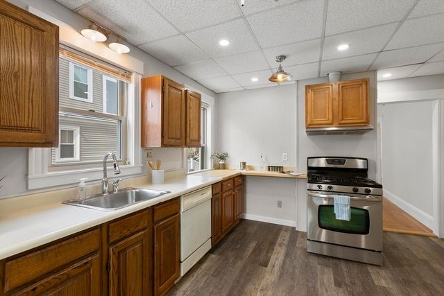 a kitchen with stainless steel appliances granite countertop wooden cabinets a sink a stove a microwave and wooden floors