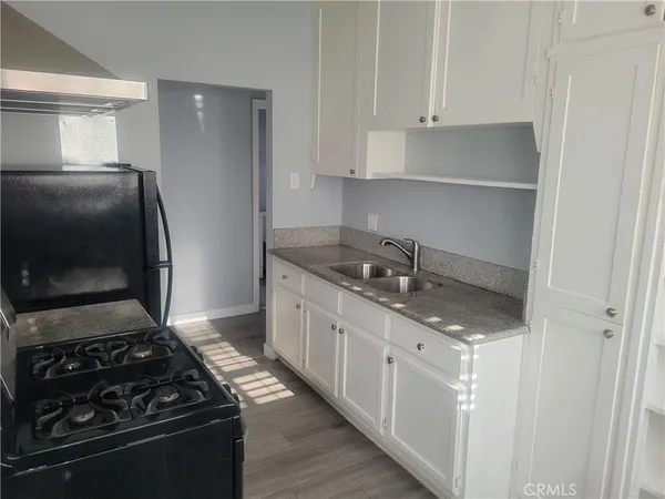 a kitchen with granite countertop a sink stove and refrigerator