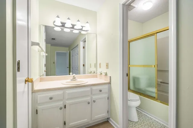 a bathroom with a sink a toilet and shower a mirror