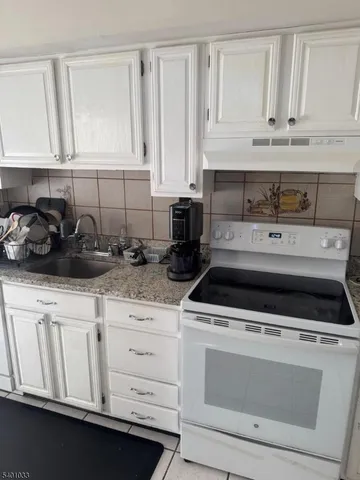 a kitchen with white cabinets and appliances