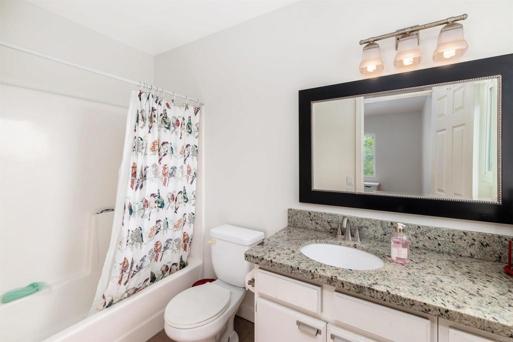 4239 Vista Del Rio Way, Unit 6 Oceanside, CA 92057 - Photo 23 of 30 a bathroom with a granite countertop sink a toilet and a mirror